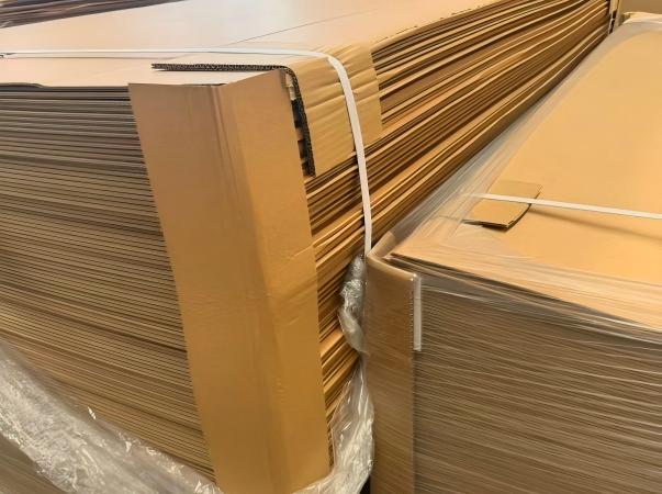 Una fotograf&iacute;a que muestra la protecci&oacute;n integrada 'libre de da&ntilde;os' de Juhong Packing para paletas de cart&oacute;n corrugado. Primero, la carga se envuelve en una pel&iacute;cula LLDPE de alta elasticidad para proporcionar una barrera contra la humedad y distribuir uniformemente la presi&oacute;n lateral, evitando el 'aplastamiento de la flauta' cr&iacute;tico de la estructura corrugada hueca. Luego se asegura estructuralmente con blanco virgen de alta limpieza PET Fleje . Como redactor de normas nacionales (GB/T 39040—2020), Juhong dise&ntilde;&oacute; esta soluci&oacute;n para exportaciones de papel de alto valor que exigen estabilidad estructural y una presentaci&oacute;n impecable.